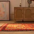 Handmade red and orange Persian-style wool and cotton Kilim runner rug with geometric patterns on a wooden floor.
