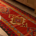 Handmade 3x11 ft red and orange Persian-style wool-cotton Kilim runner with geometric bohemian patterns.