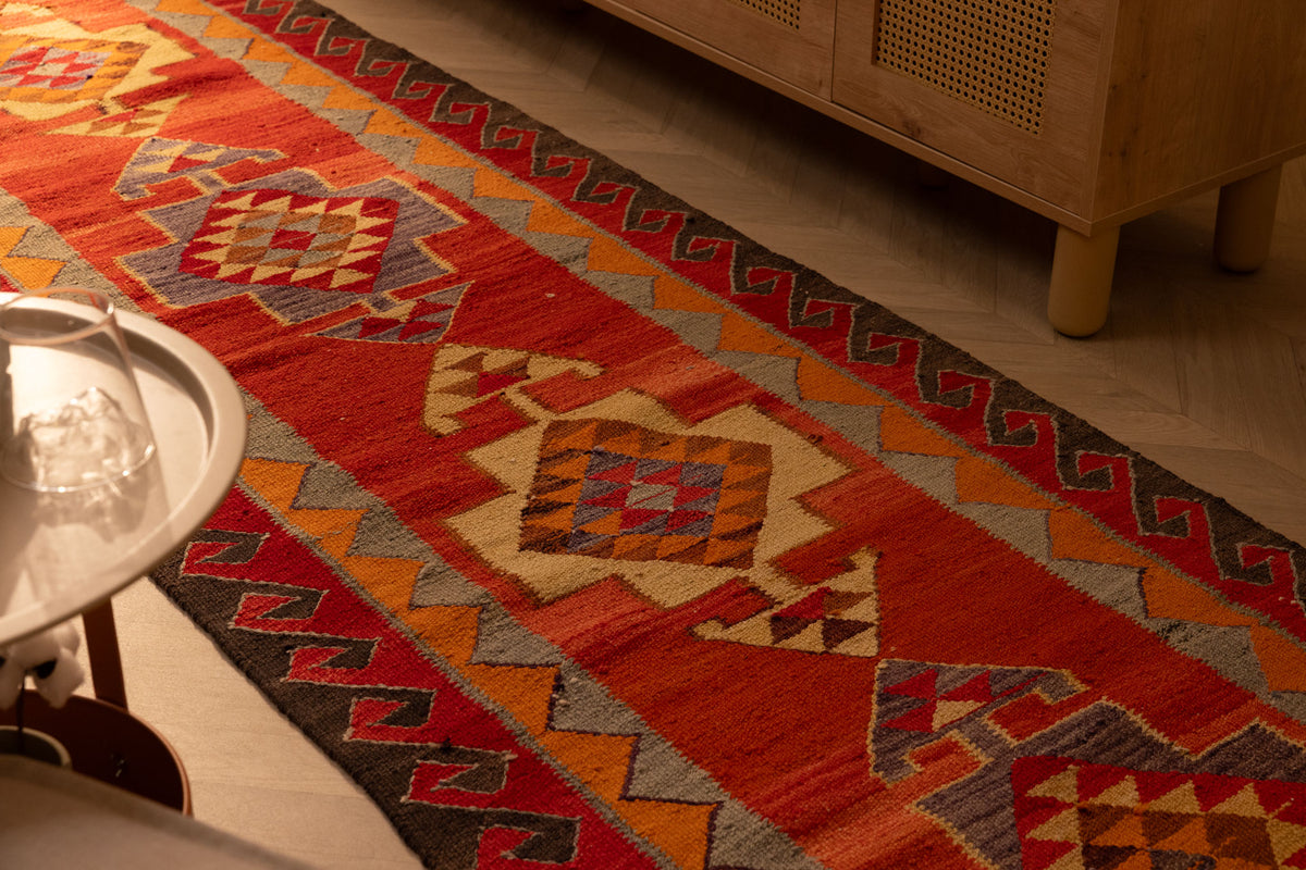 Handmade 3x11 ft red and orange Persian-style wool-cotton Kilim runner with geometric bohemian patterns.