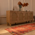 Handmade pink and beige Persian-style wool and cotton runner rug with geometric patterns on a wooden floor.