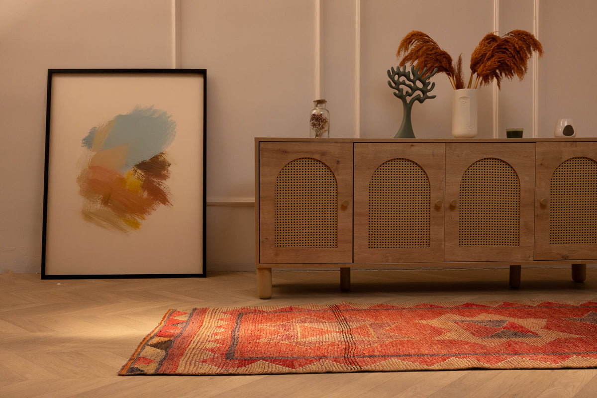 Handwoven pink and beige Persian-style wool and cotton runner rug with geometric patterns on a wooden floor.