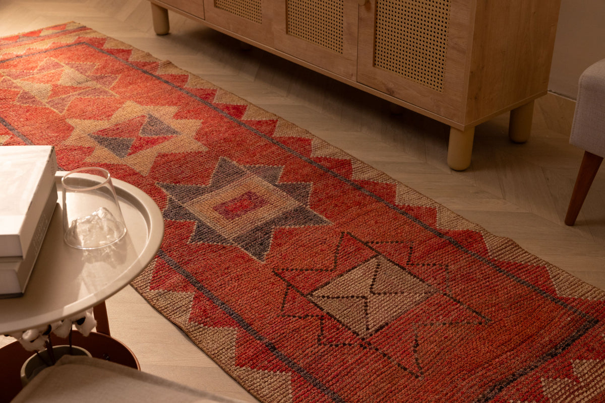 Handwoven pink and beige wool-cotton Persian runner rug with geometric patterns, 2.8 x 10.4 ft, in a bohemian interior.