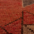 Close-up of a pink and beige wool-cotton Persian runner rug with geometric patterns and a textured low-pile weave.