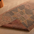 Handmade pink and brown wool-cotton Persian runner rug with geometric patterns on a wooden floor.