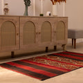 Handmade 3x5 ft vintage Turkish wool kilim rug in red and brown with geometric patterns on a wooden floor.