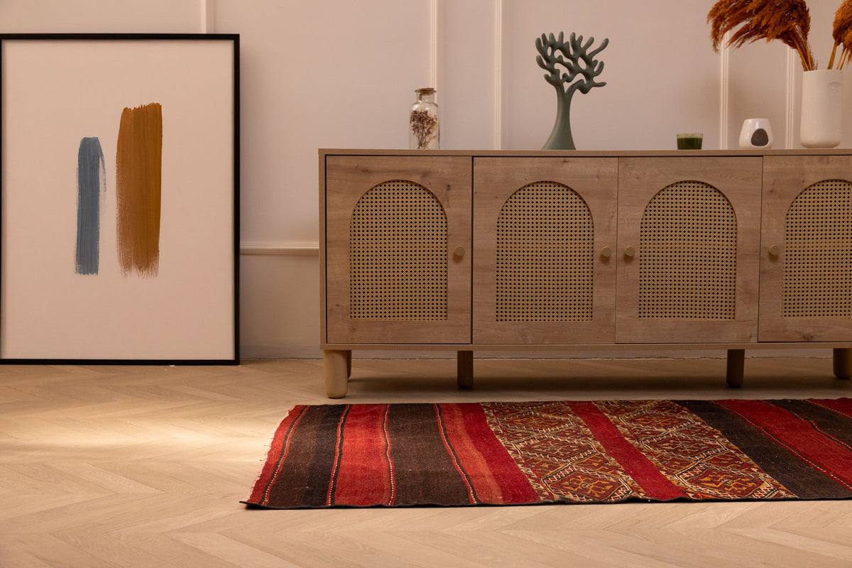 Handmade vintage Turkish wool kilim rug in red and brown with geometric patterns on a wooden floor.