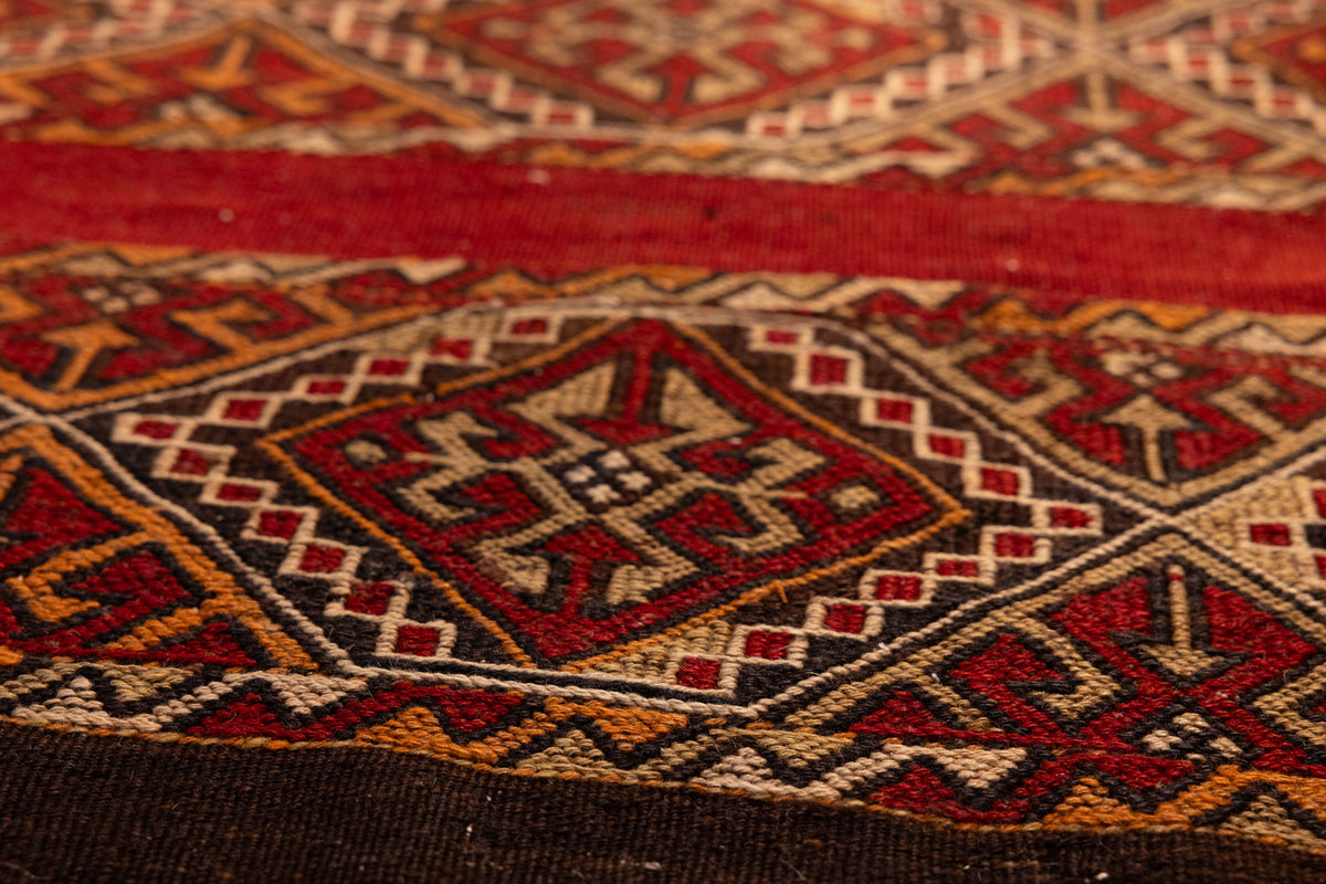 Handmade vintage Turkish wool kilim rug featuring red and brown geometric patterns in a flatweave design.