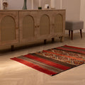 Handmade 3x4 ft vintage Turkish wool kilim rug featuring red and brown geometric patterns on a herringbone floor.