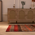 Handmade 3x4 ft wool Turkish kilim rug in red and brown with geometric patterns on a light wood floor.