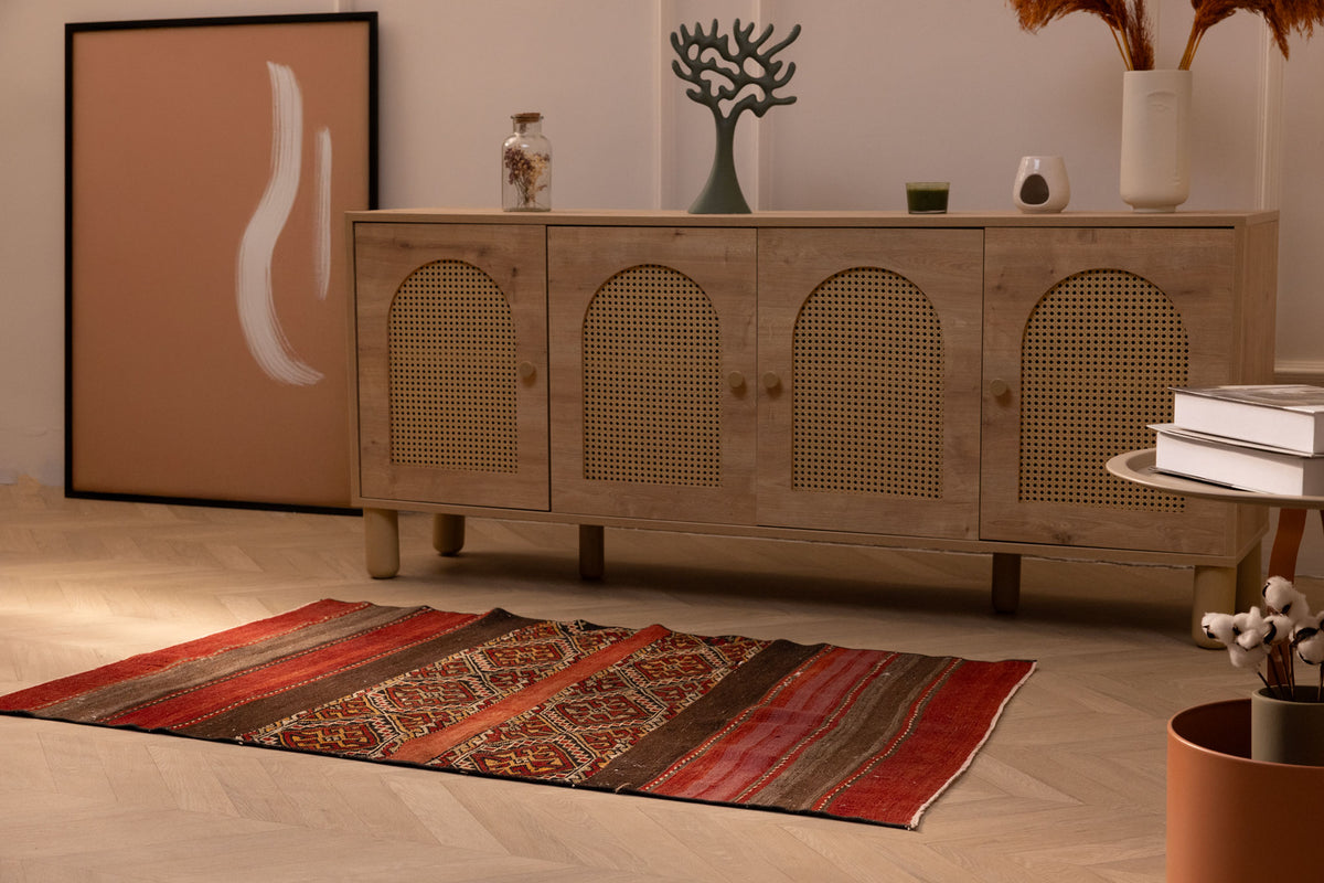 Hand-woven 3x4 ft vintage Turkish wool rug in red and brown with geometric patterns on a light wood floor.
