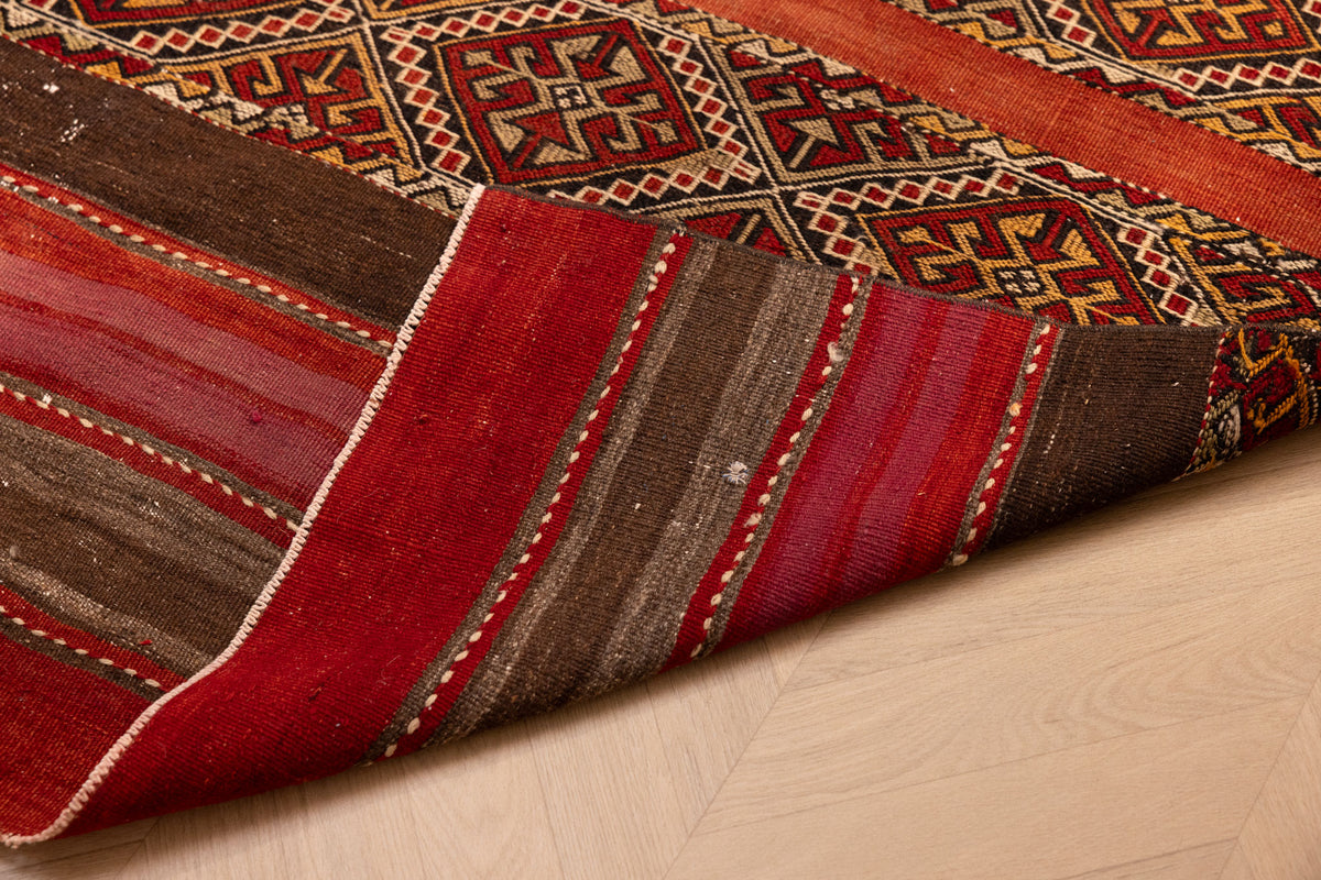 Handmade vintage Turkish wool kilim rug in red and brown with geometric patterns and a striped flatweave design.
