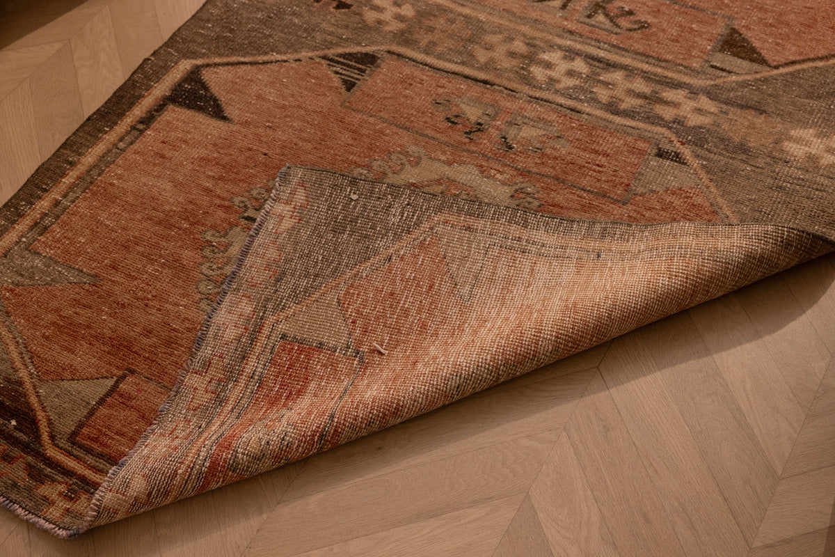 Handwoven vintage Turkish runner rug in orange and brown with geometric patterns, crafted from wool and cotton.