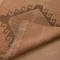 Vintage 3x12 ft Turkish runner rug in orange and brown wool with geometric tribal patterns and a folded corner.