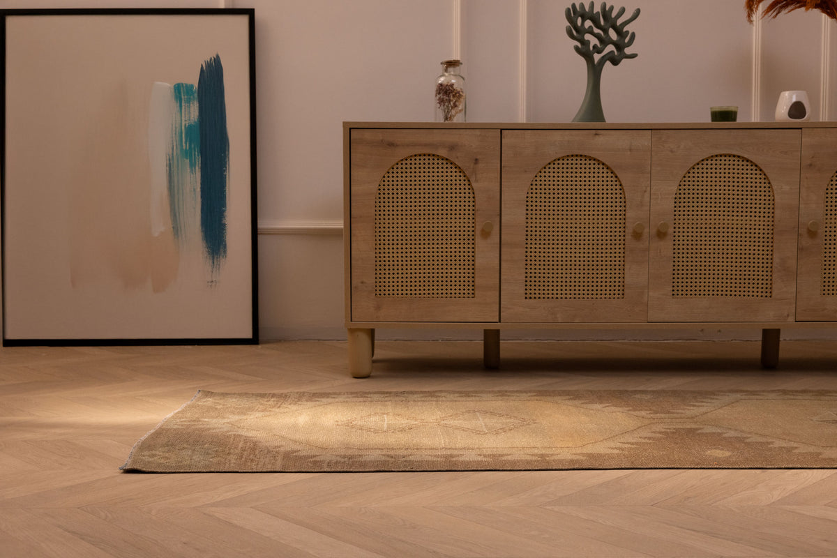 Vintage brown and beige geometric Turkish wool runner rug on a light wood floor in a farmhouse-style room.