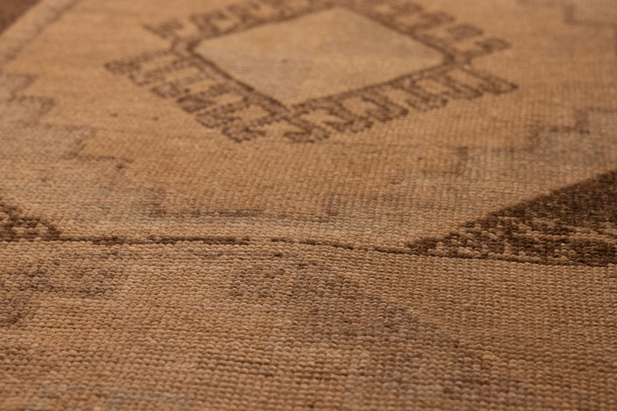 Handwoven vintage Turkish runner rug in beige and brown wool with intricate geometric patterns and low pile texture.