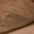 Hand-woven vintage Turkish runner rug in beige and brown wool with geometric patterns and a folded corner.
