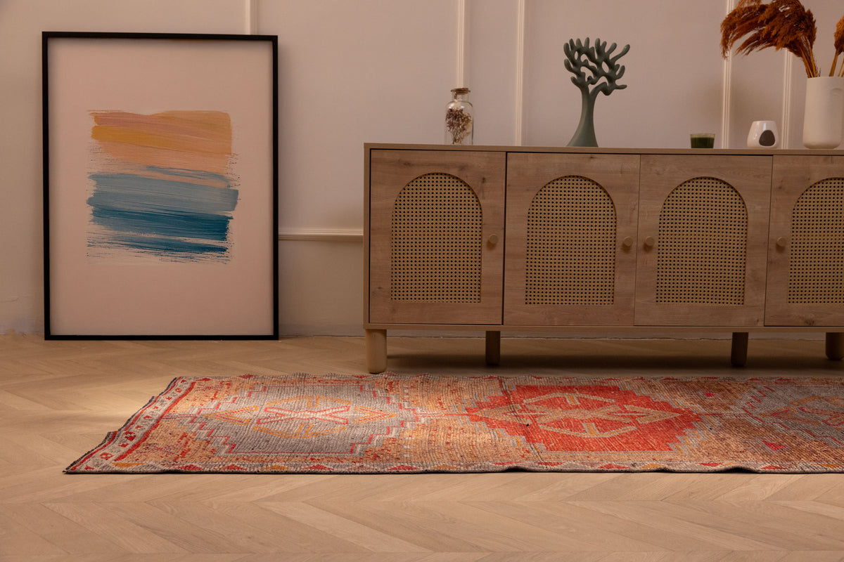 Handmade wool and cotton Persian style runner rug in orange and brown with geometric patterns on a wooden floor.