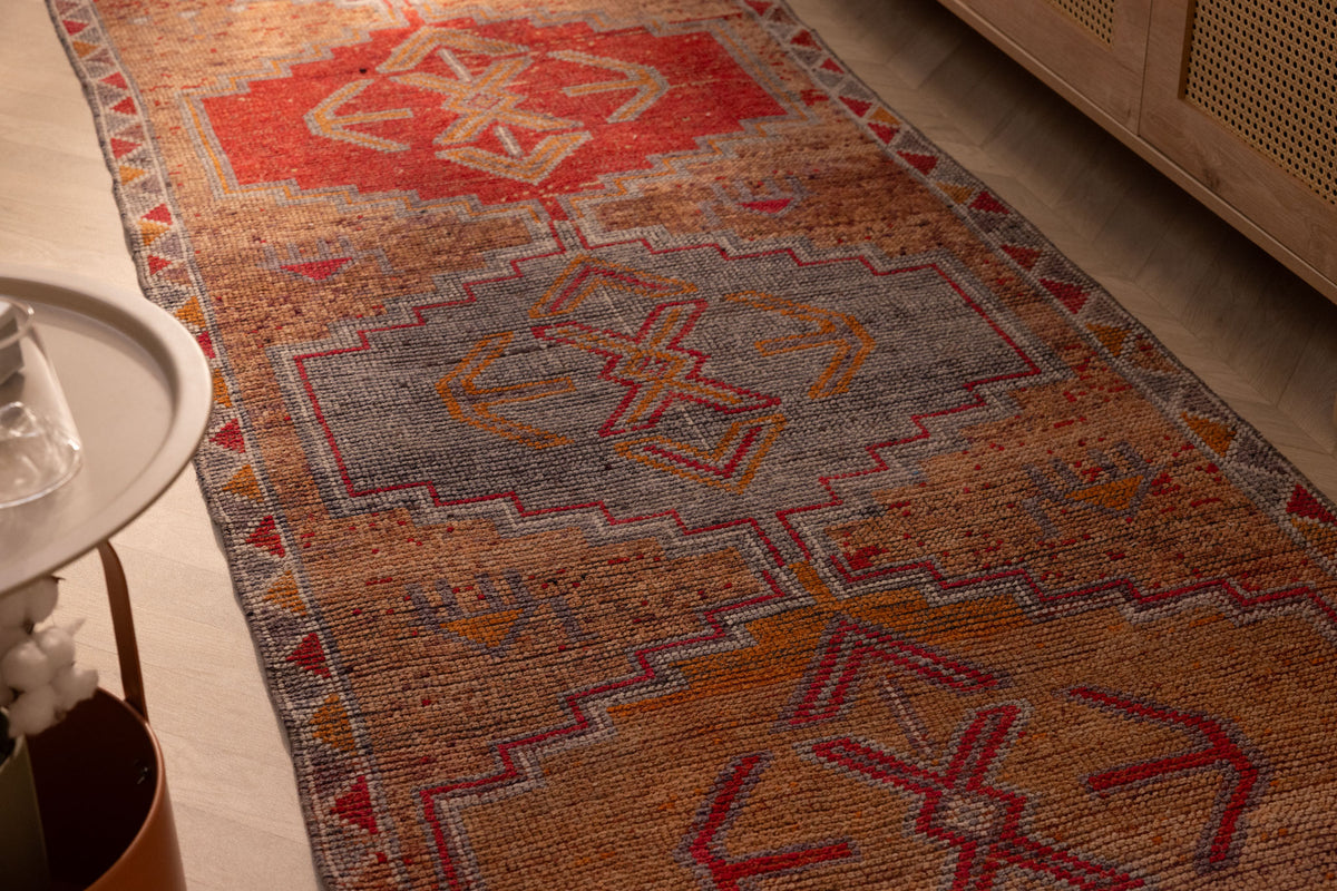Handmade 3.4 x 10.3 ft wool and cotton Persian-style runner rug featuring orange and brown geometric bohemian patterns.