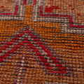 Close-up of a handmade wool and cotton Persian runner rug featuring orange and brown geometric patterns.