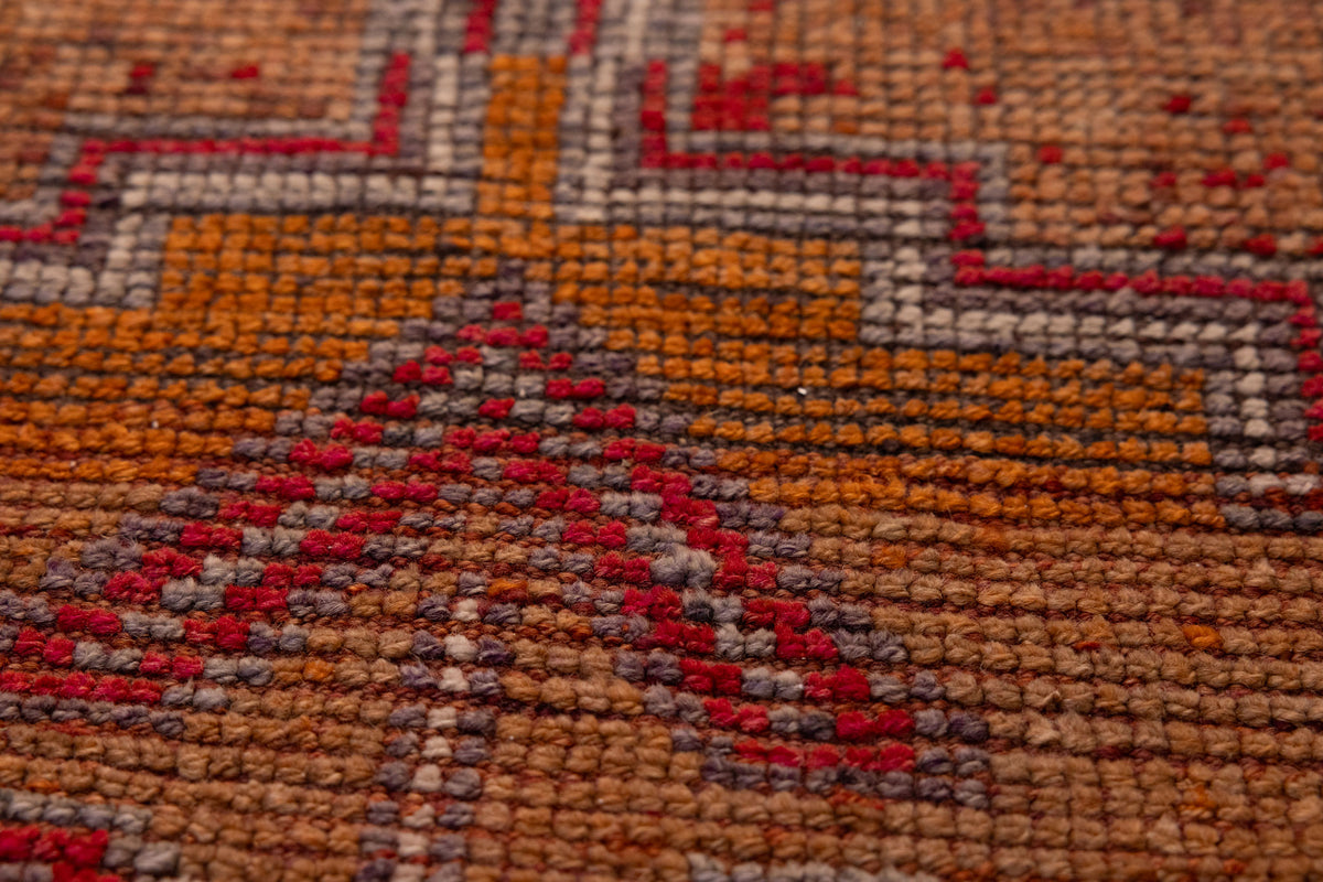 Close-up of a handmade wool and cotton Persian runner rug featuring orange and brown geometric patterns.