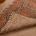 Handwoven vintage Turkish runner rug in brown and orange with geometric patterns, showing wool and cotton weave texture.