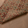 Vintage 2x8 ft handmade Turkish runner rug in beige and green with floral patterns on a herringbone wood floor.