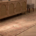 Handmade pink and beige Persian style wool-cotton runner rug with geometric patterns on a herringbone wood floor.