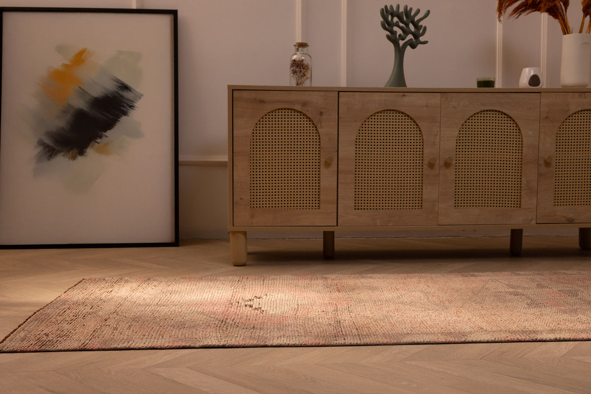 Handmade pink and beige wool-cotton Persian style runner rug with geometric patterns on a wooden floor.