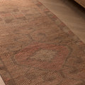 Handmade pink and beige wool-cotton Persian style runner rug with geometric patterns on a wooden floor.