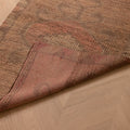 Handmade pink and beige wool-cotton Persian style runner rug with geometric patterns on herringbone wood flooring.