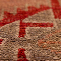 Close-up of a handmade wool and cotton Persian runner rug featuring brown and red floral patterns in a bohemian style.