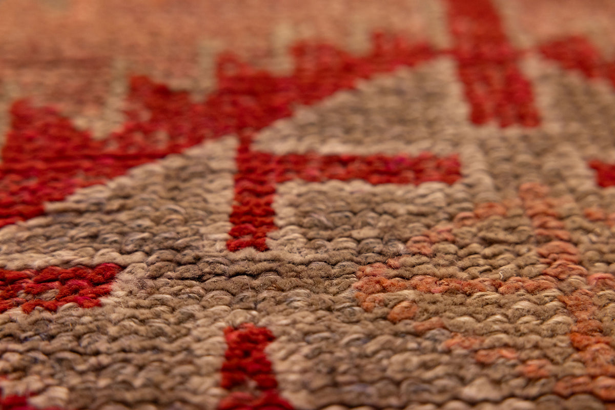 Close-up of a handmade wool and cotton Persian runner rug featuring brown and red floral patterns in a bohemian style.