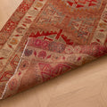 Handmade brown and red Persian-style wool-cotton runner rug with floral and geometric patterns on a wooden floor.
