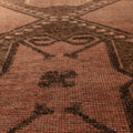 Handwoven vintage Turkish runner rug in brown and orange wool with geometric tribal patterns and a low-pile texture.