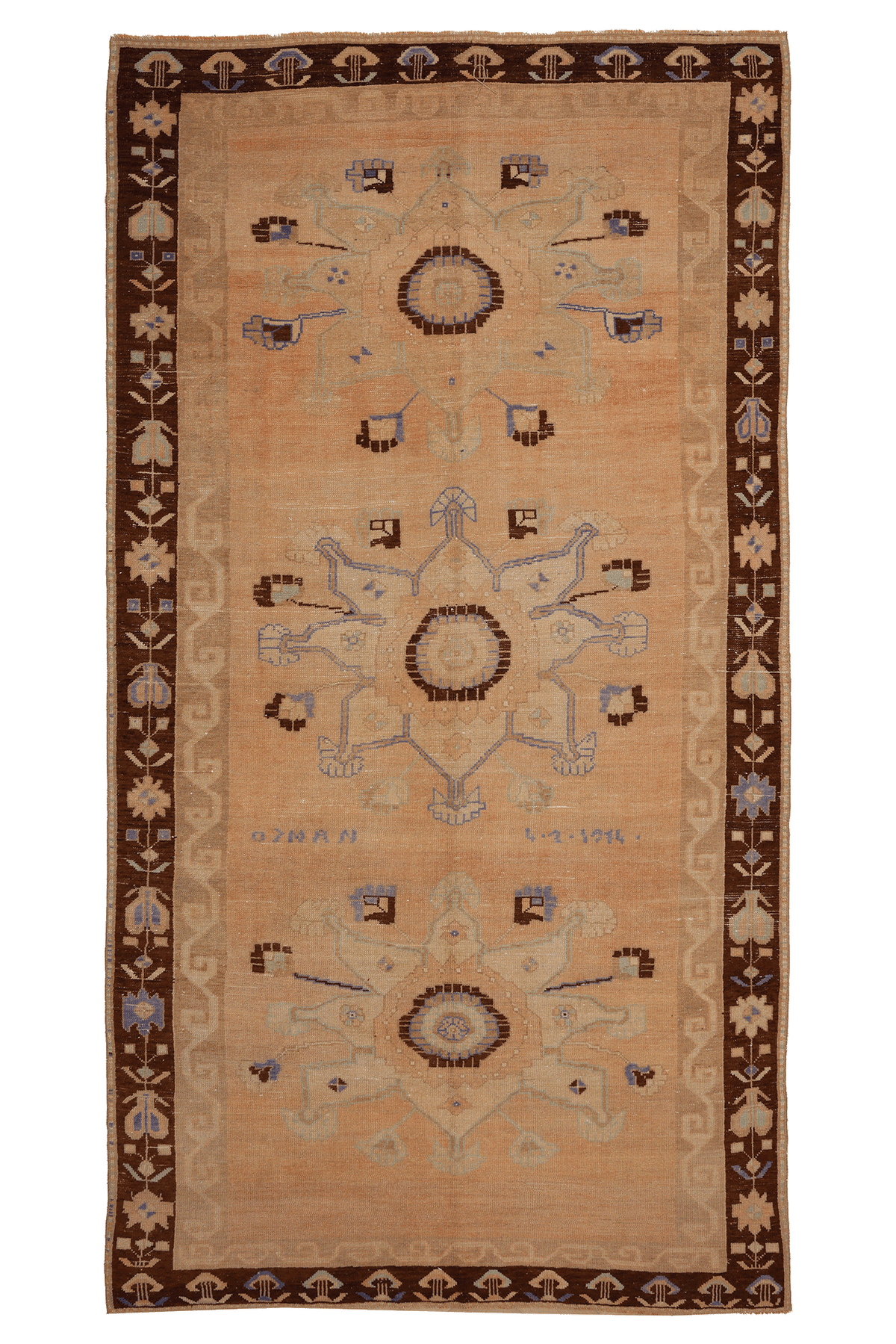 A rectangular vintage-style rug with a warm beige center field, dark brown border, and three large central medallions in muted blue, brown, and beige tones.