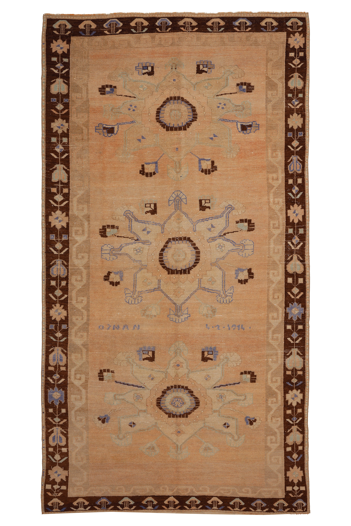 A rectangular vintage-style rug with a warm beige center field, dark brown border, and three large central medallions in muted blue, brown, and beige tones.
