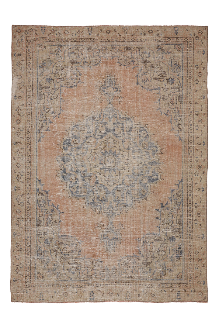 A distressed vintage-style oriental rug with a central medallion, featuring a dusty peach-pink field, faded blue motifs, and a beige border.
