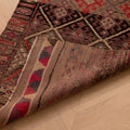Handmade brown wool and cotton Persian-style runner rug with geometric maximalist patterns on a wooden floor.