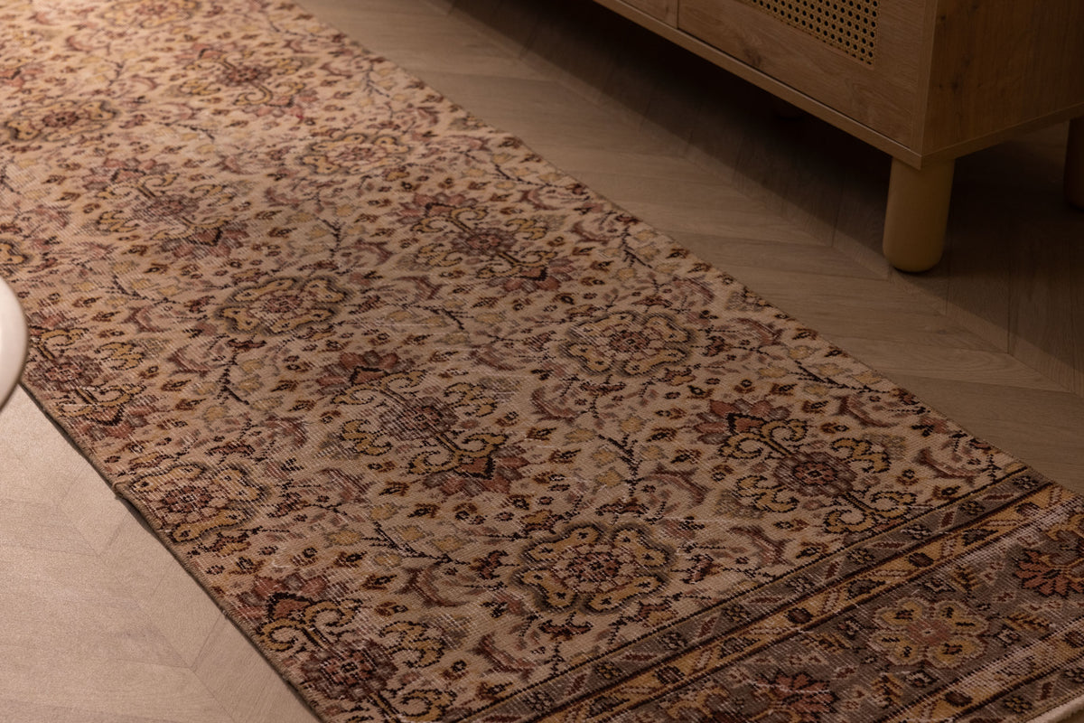 Vintage handmade Isparta wool and cotton runner rug with white and beige floral maximalist patterns on a wooden floor.