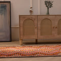 Handmade 3x11 ft Persian-style wool and cotton kilim runner with pink and orange geometric patterns on a wooden floor.