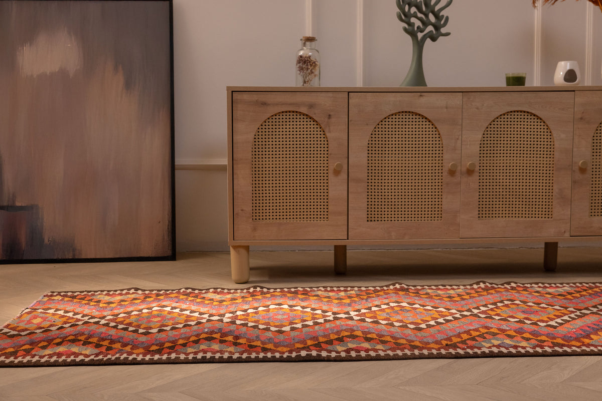 Handmade 3x11 ft Persian-style wool and cotton kilim runner with pink and orange geometric patterns on a wooden floor.