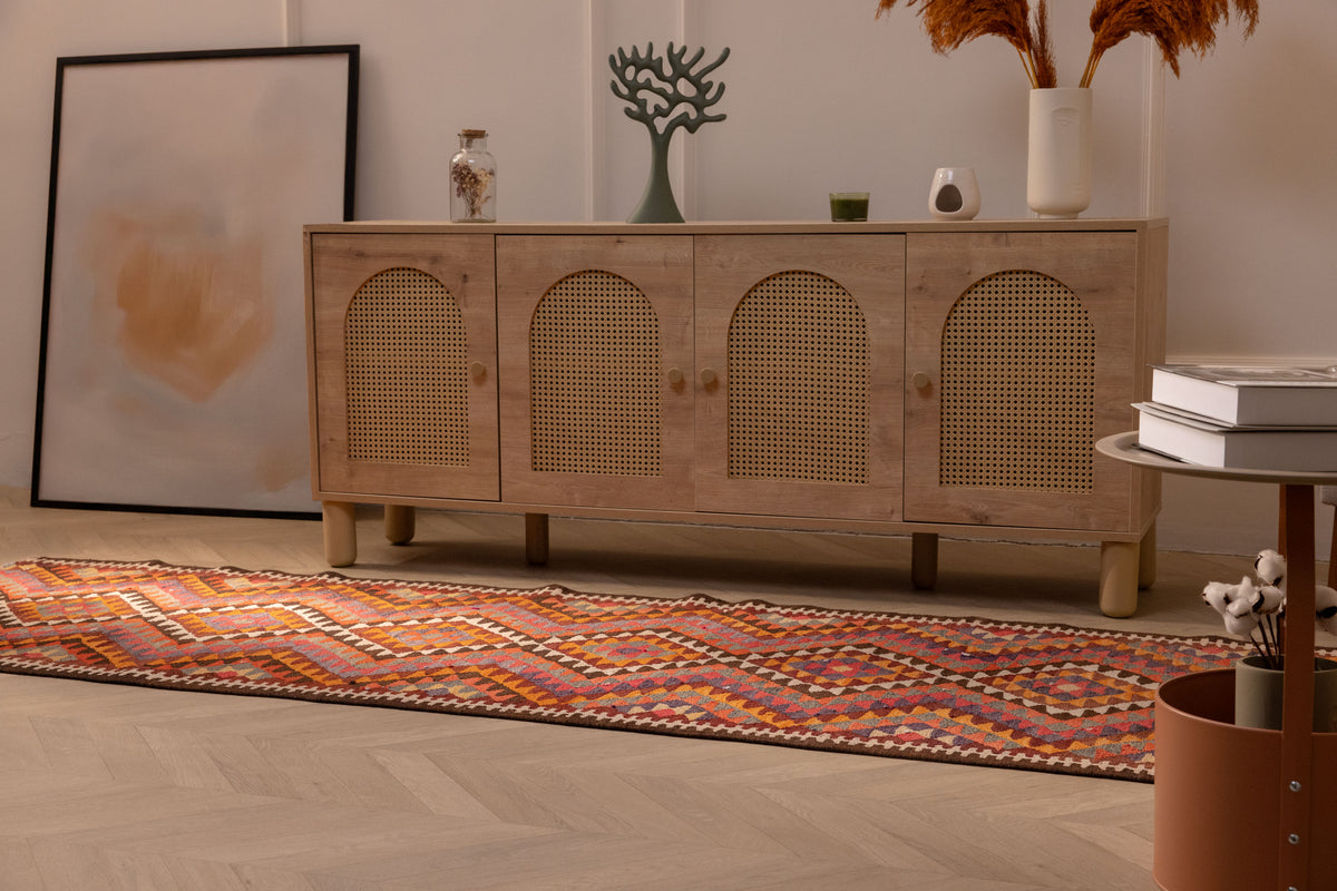 Handmade 3x11 ft wool and cotton Persian-style kilim runner with pink and orange geometric patterns on a wooden floor.