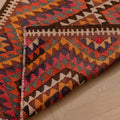 Handmade pink and orange Persian-style wool-cotton kilim runner with geometric patterns on a wooden floor.