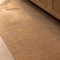 Hand-woven 2x11 ft vintage Turkish runner rug in beige and brown with geometric patterns on a wooden floor.