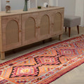 Handmade 3.4x11.3 ft wool and cotton Persian-style kilim runner in vibrant orange and pink geometric patterns.