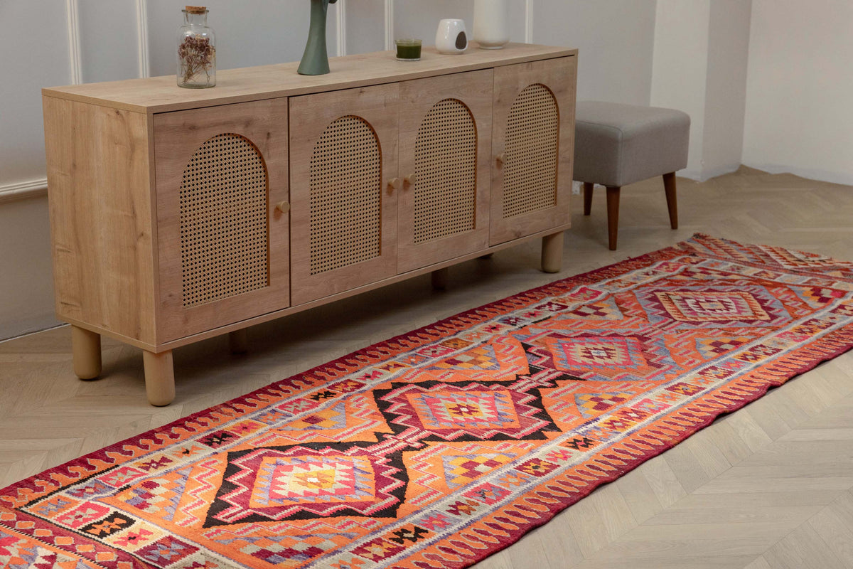 Handmade 3.4x11.3 ft wool and cotton Persian-style kilim runner in vibrant orange and pink geometric patterns.