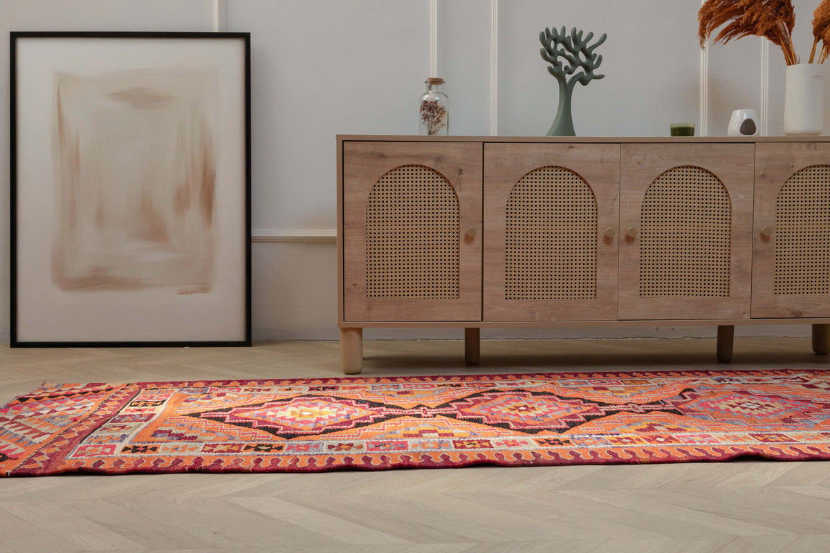 Handmade 3.4x11.3 ft wool and cotton Persian-style kilim runner in vibrant orange and pink geometric patterns.
