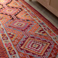 Bohemian 3x11 ft wool and cotton flatweave runner rug featuring orange and pink geometric patterns.