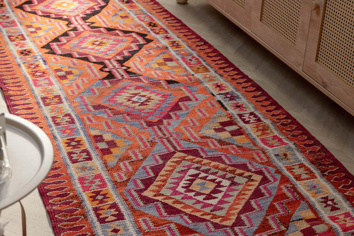 Bohemian 3x11 ft wool and cotton flatweave runner rug featuring orange and pink geometric patterns.