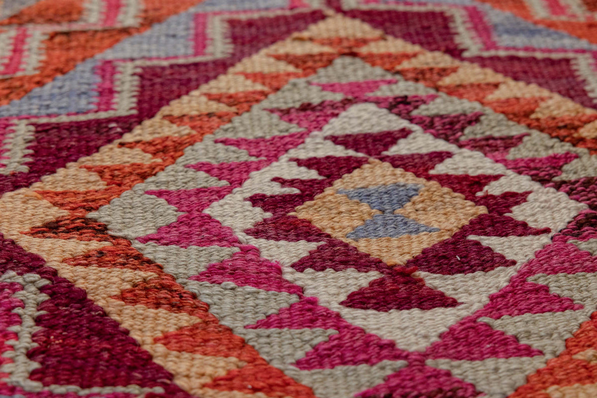 Handmade bohemian wool and cotton kilim runner with geometric pink and orange patterns.